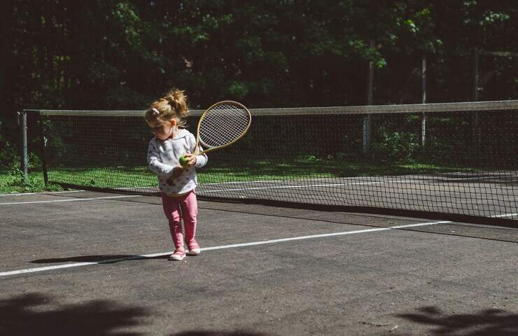 bambina gioca con racchetta su campo da tennis