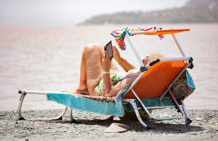 donna legge con e-reader in spiaggia