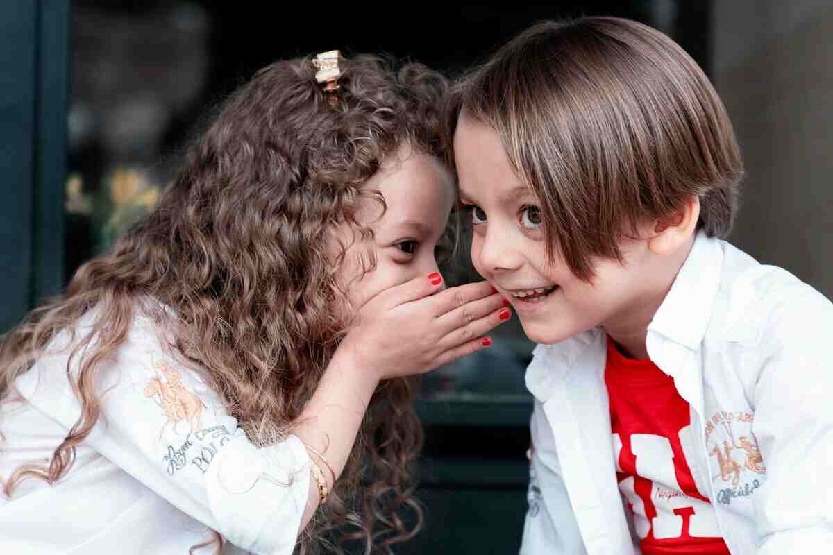 bambina parla nell'orecchio al bambino